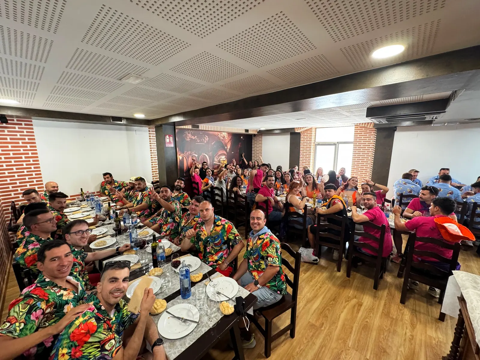 Cuadrilla con camisas de flores comiendo en mesa larga en el comedor