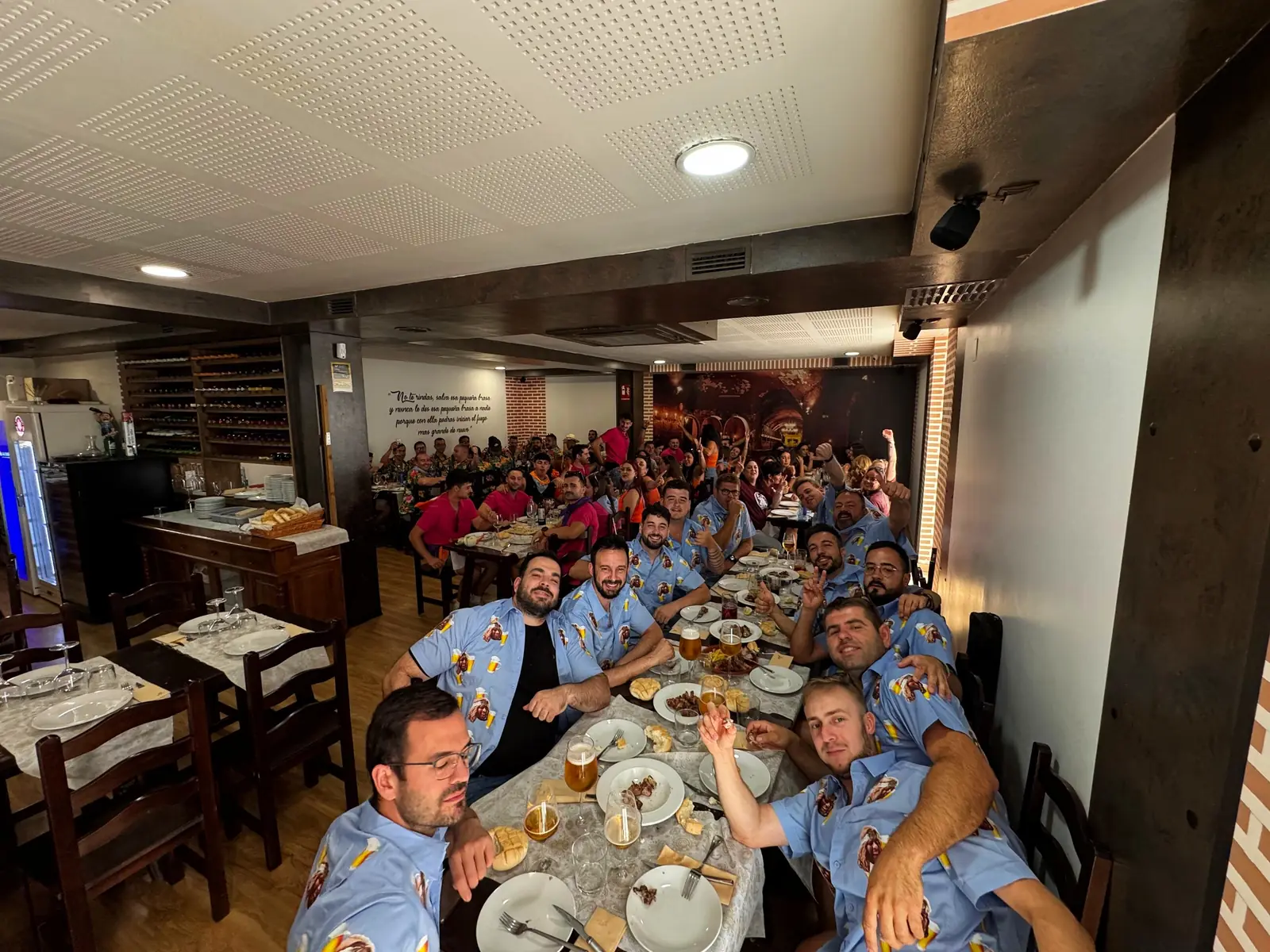 Peña con camisas iguales brindando en una mesa larga