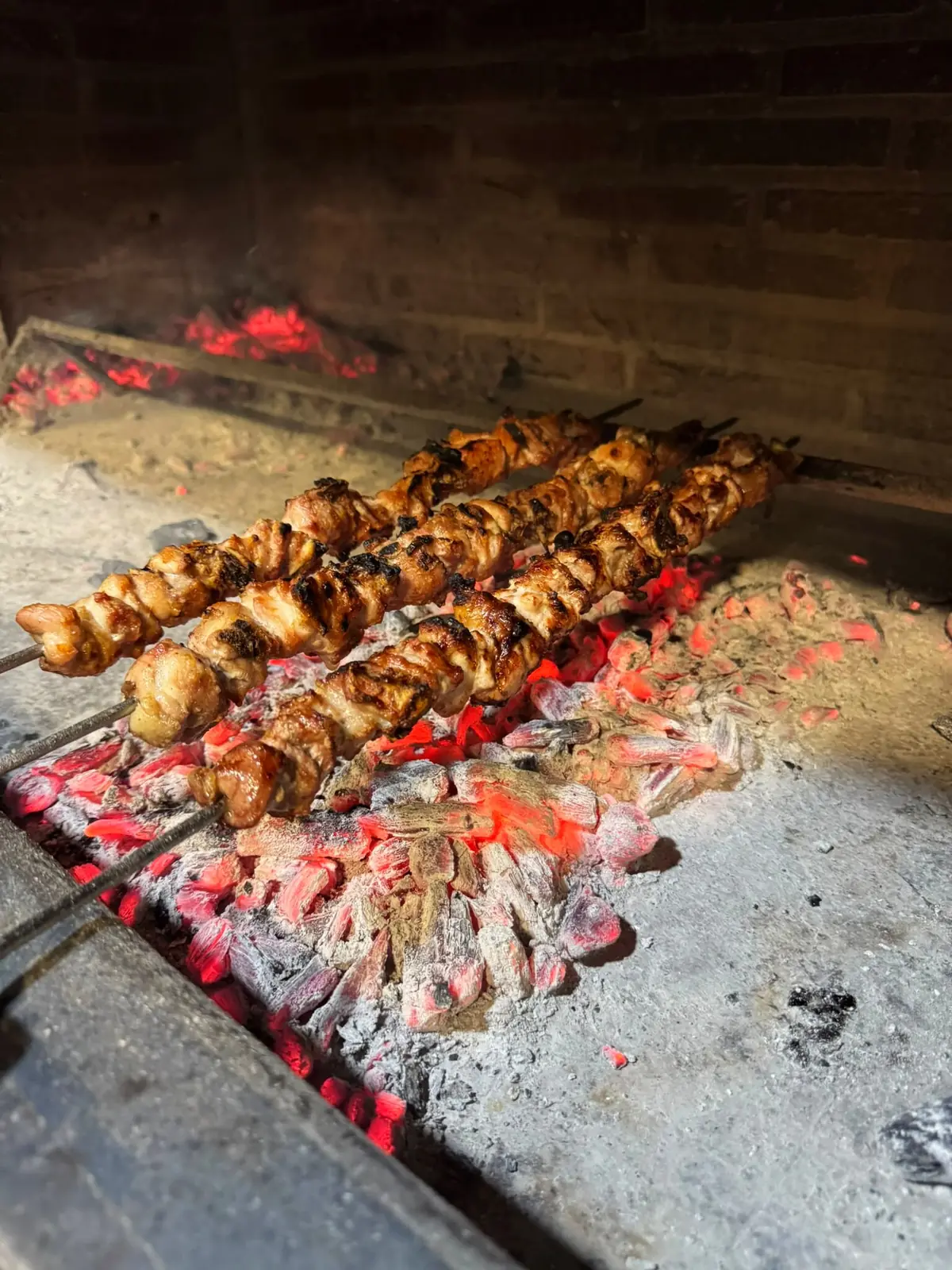 Varios pinchos asándose en fila sobre la brasa